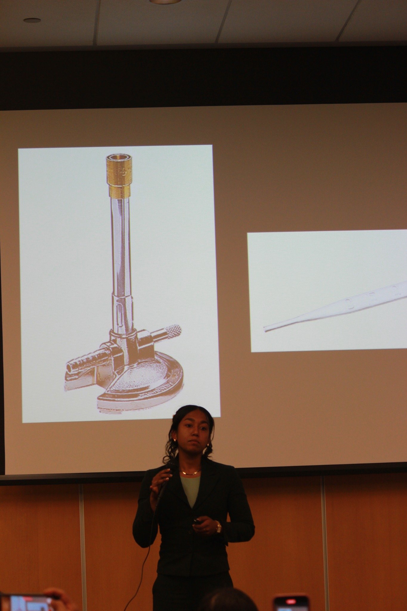 Ariana Rahman presenting on stage with projected images behind her